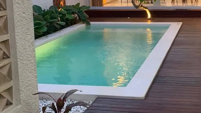 Courtyard pool with soft lighting beside a timber deck in the evening