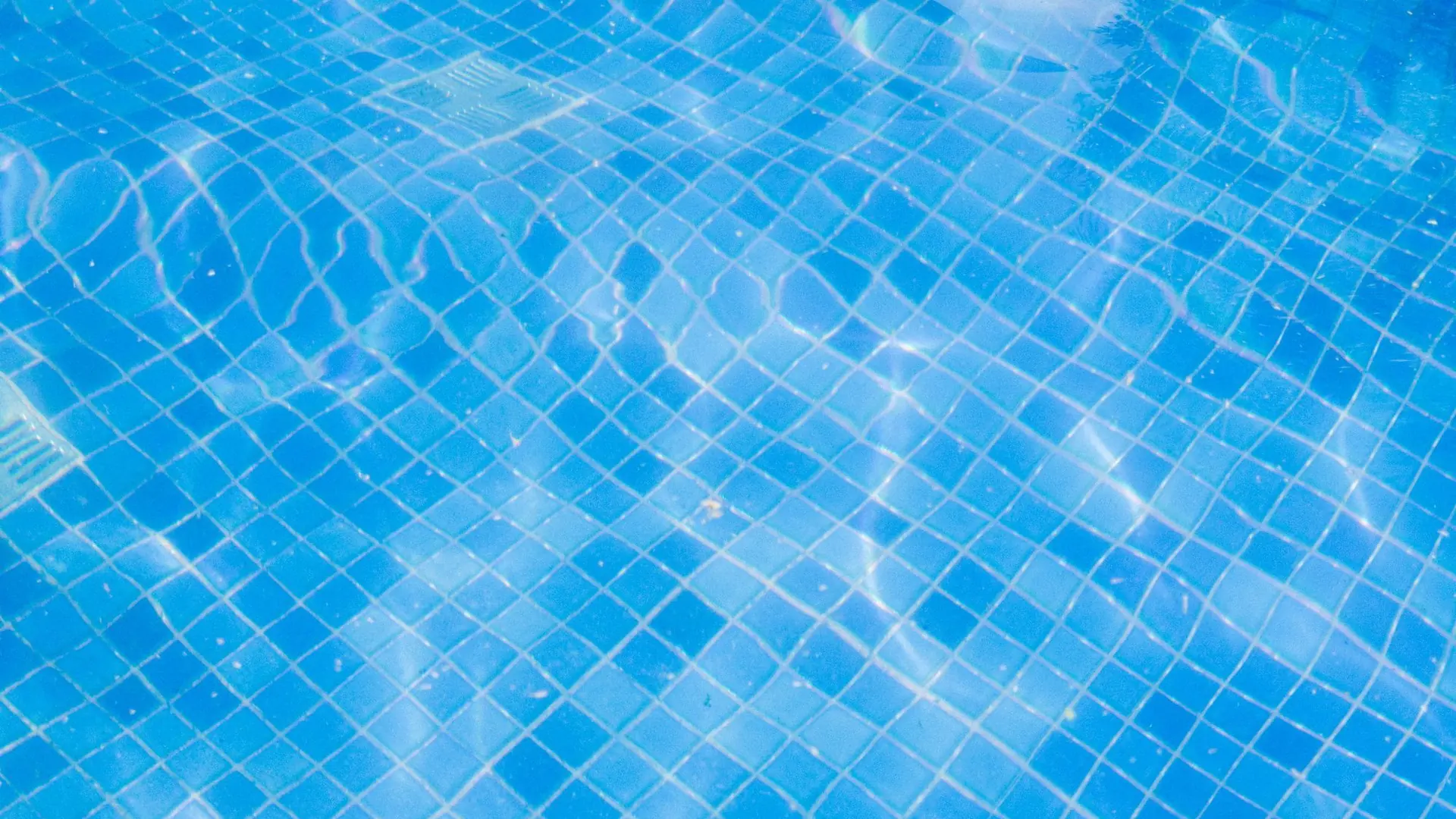 Illustrative close-up of blue pool tiles under rippling water